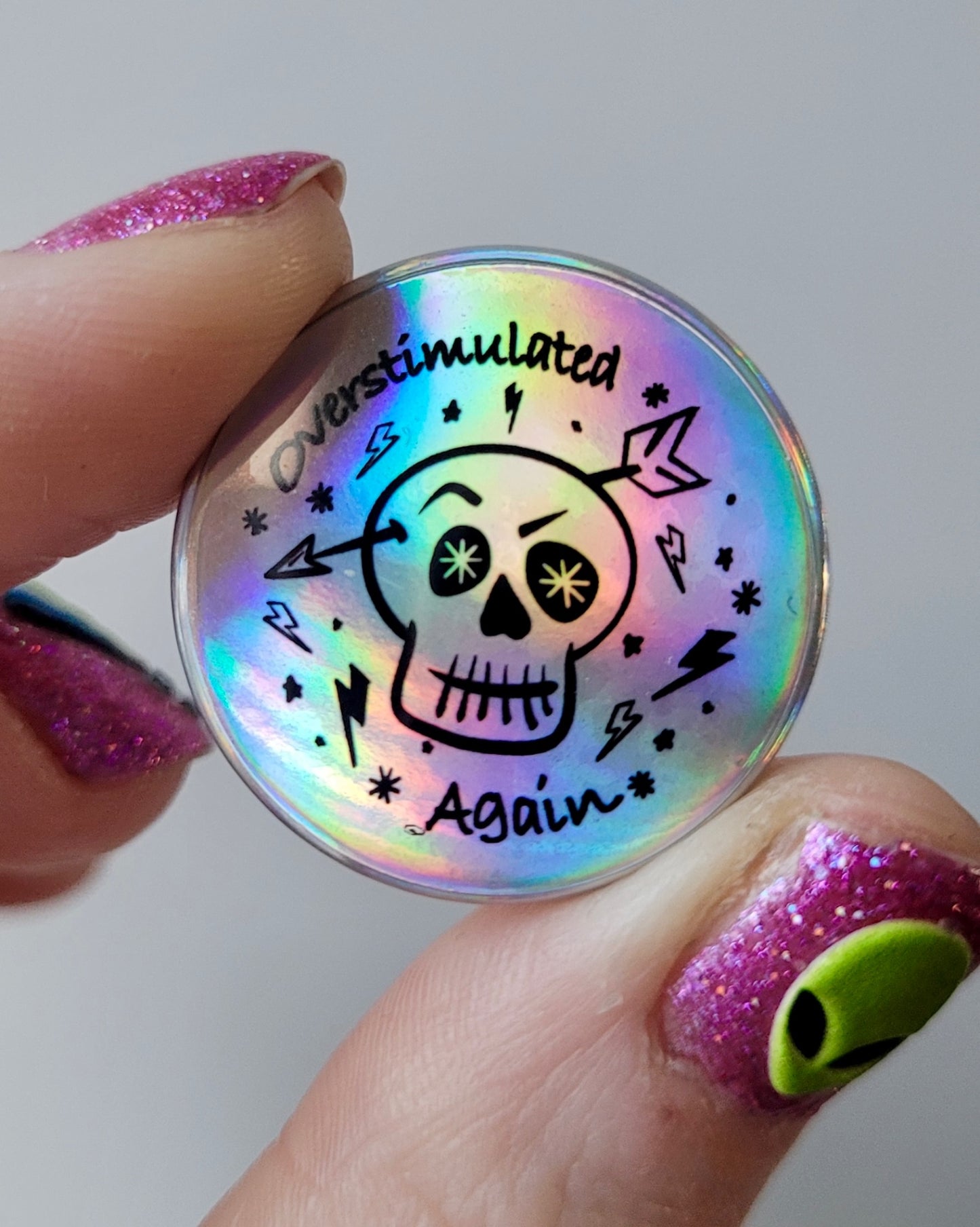 “Overstimulated Again” Holographic Skull Badge – Neurodivergent Alt Pin