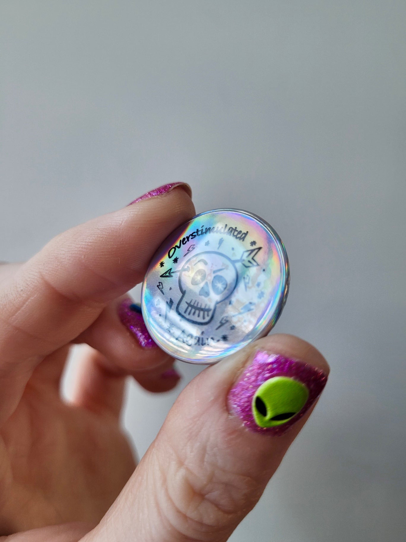 “Overstimulated Again” Holographic Skull Badge – Neurodivergent Alt Pin