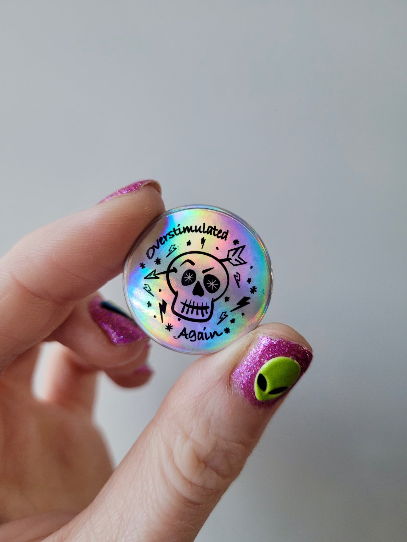 “Overstimulated Again” Holographic Skull Badge – Neurodivergent Alt Pin